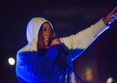 Keysha Freshh performs on an outdoor stage with blue lighting for Vanguard Voices in Hip Hop.
